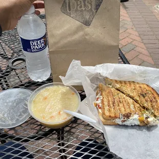 a person holding a sandwich and a bowl of soup