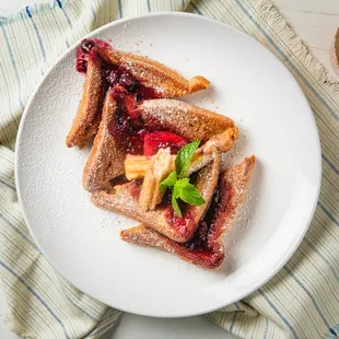 Churro French Toast-thick brioche, cinnamon sugar, berry coulis, topped with powdered sugar.