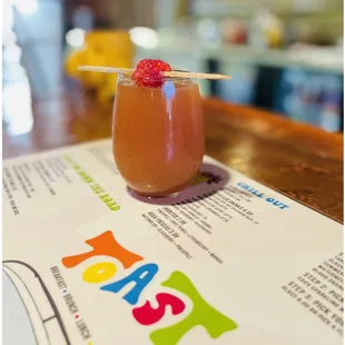 a drink with a straw and a raspberry garnish