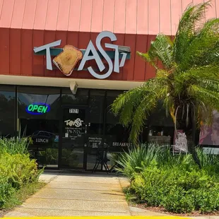 the entrance to a restaurant with palm trees