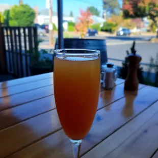 a glass of orange juice on a wooden table