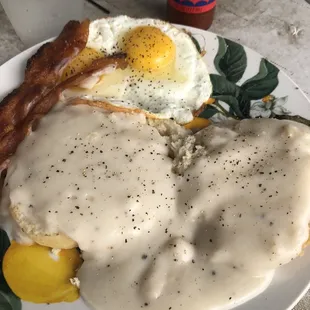 Biscuits and gravy, sunny side up eggs, and bacon