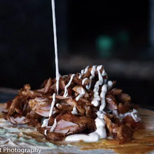 a close up of a taco with sauce drizzled over it