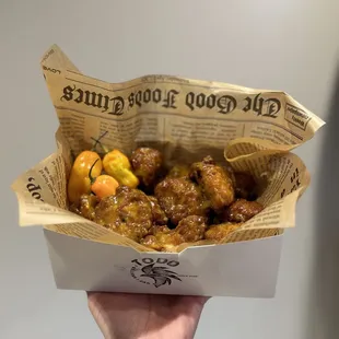 a hand holding a box of food