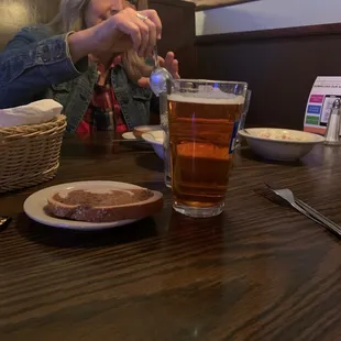 a woman sitting at a table with a glass of beer
