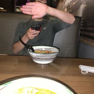 a man sitting at a table with a bowl of soup in front of him