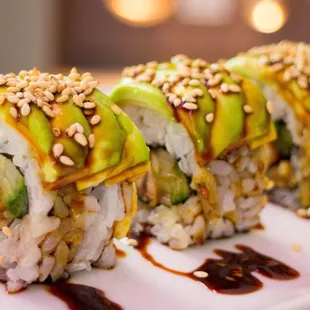a sushi roll with avocado and sesame seeds