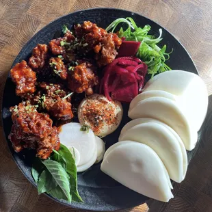 Fried Chicken Steam buns- karaage fried chicken tossed in sweet chili sauce served with kewpie mayo, pickles, scallions and cilantro