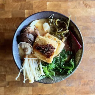 vegan ramen- soy, mushroom and charred vegetable broth served with tofu, enoki mushrooms, house pickles, kelp, miso chili crisp