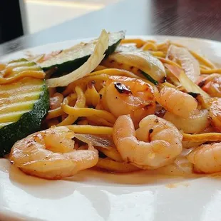 a plate of shrimp, zucchini, and noodles