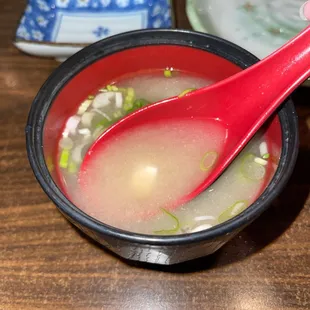 a red spoon in a bowl of soup