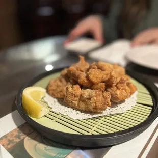 a plate of fried chicken with a lemon wedge