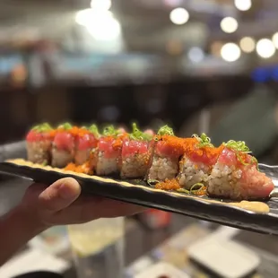 a person holding a plate of sushi