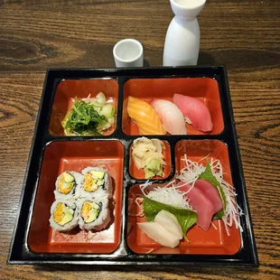 a tray of sushi and vegetables on a wooden table