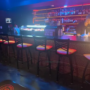 a bar with stools and neon lights