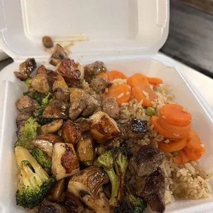 a takeout container with rice, meat, and vegetables