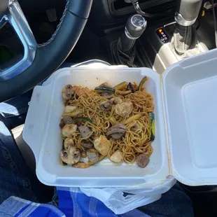 a take out container of noodles and meat