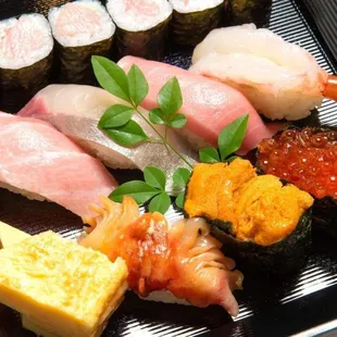 a variety of sushi on a black plate