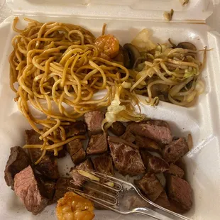 a take out container with noodles, meat, and vegetables