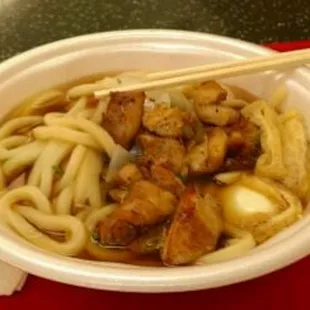a bowl of noodles and meat with chopsticks