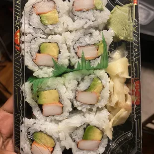 a person holding a plastic container of sushi