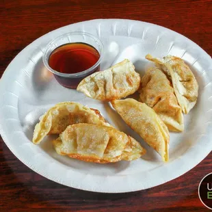a plate of dumplings with dipping sauce