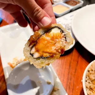 a hand holding a piece of sushi