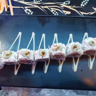 a sushi roll with white sauce on a black plate