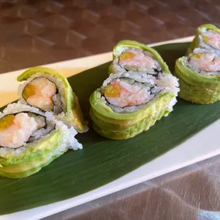 three sushi rolls on a leaf