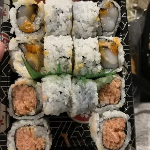 a hand holding a tray of sushi