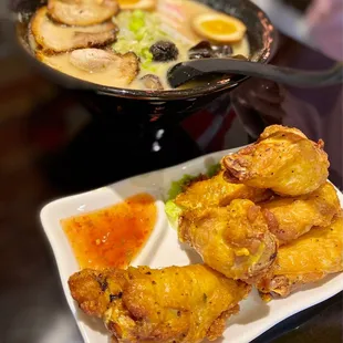 a bowl of ramen and a plate of chicken wings