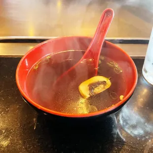 a bowl of hot soup with a red spoon