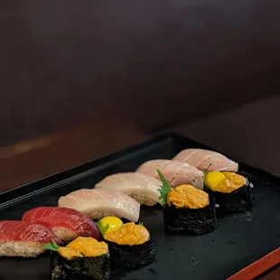 a variety of sushi on a black plate