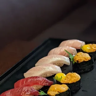 a variety of sushi on a black plate