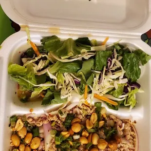 a takeout container with a salad in it