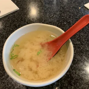 a bowl of soup with a red spoon