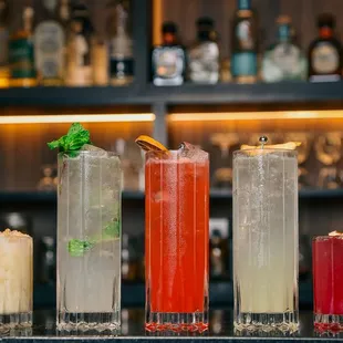 a row of cocktails on a bar