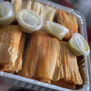 a person holding a tray of tamales