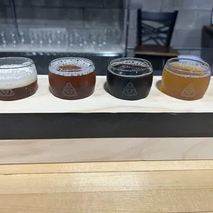 a flight of beers on a wooden tray