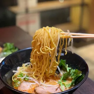 chopsticks lifting noodles from a bowl