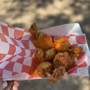 a person holding a basket of fried wings