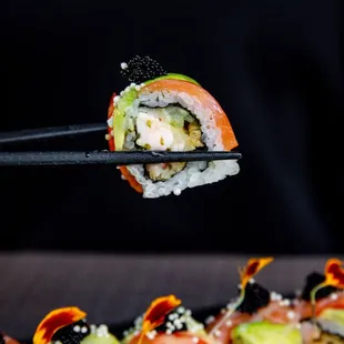 a close up of a sushi roll being held by a pair of chopsticks