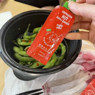 a hand holding a packet of tomo noodles