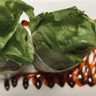 two lettuce wrapped in lettuce on a white plate
