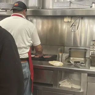 Employee flipping and touching raw burgers with his bare hands.