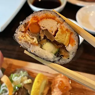 a person holding chopsticks over a sushi