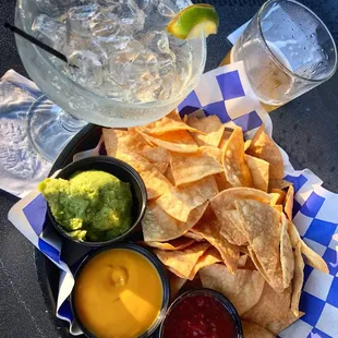 a plate of chips, guacamole, and a drink