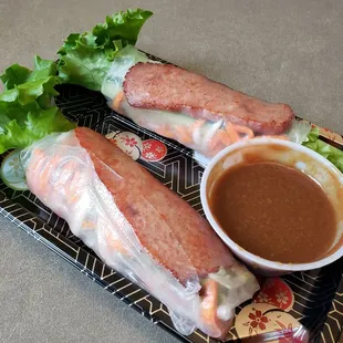 two rolls of meat and lettuce with dipping sauce