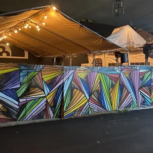 a colorful wall with a tent in the background