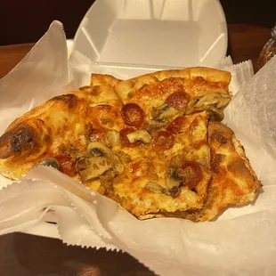two slices of pizza in a styrofoam container
